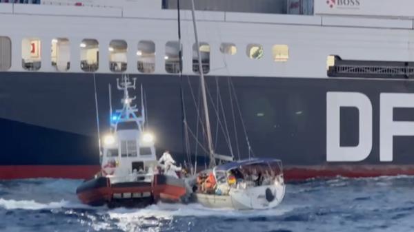 Rescuers from the coast guard trying to board the sailboat in the lee of a cargo ship on June 17, 2023 | Photo: Screenshot from Guardia Costiera video